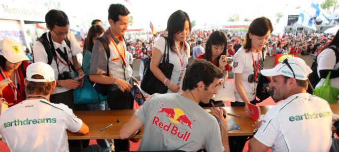 Mark Webber y Rubens Barrichello firman autógrafos